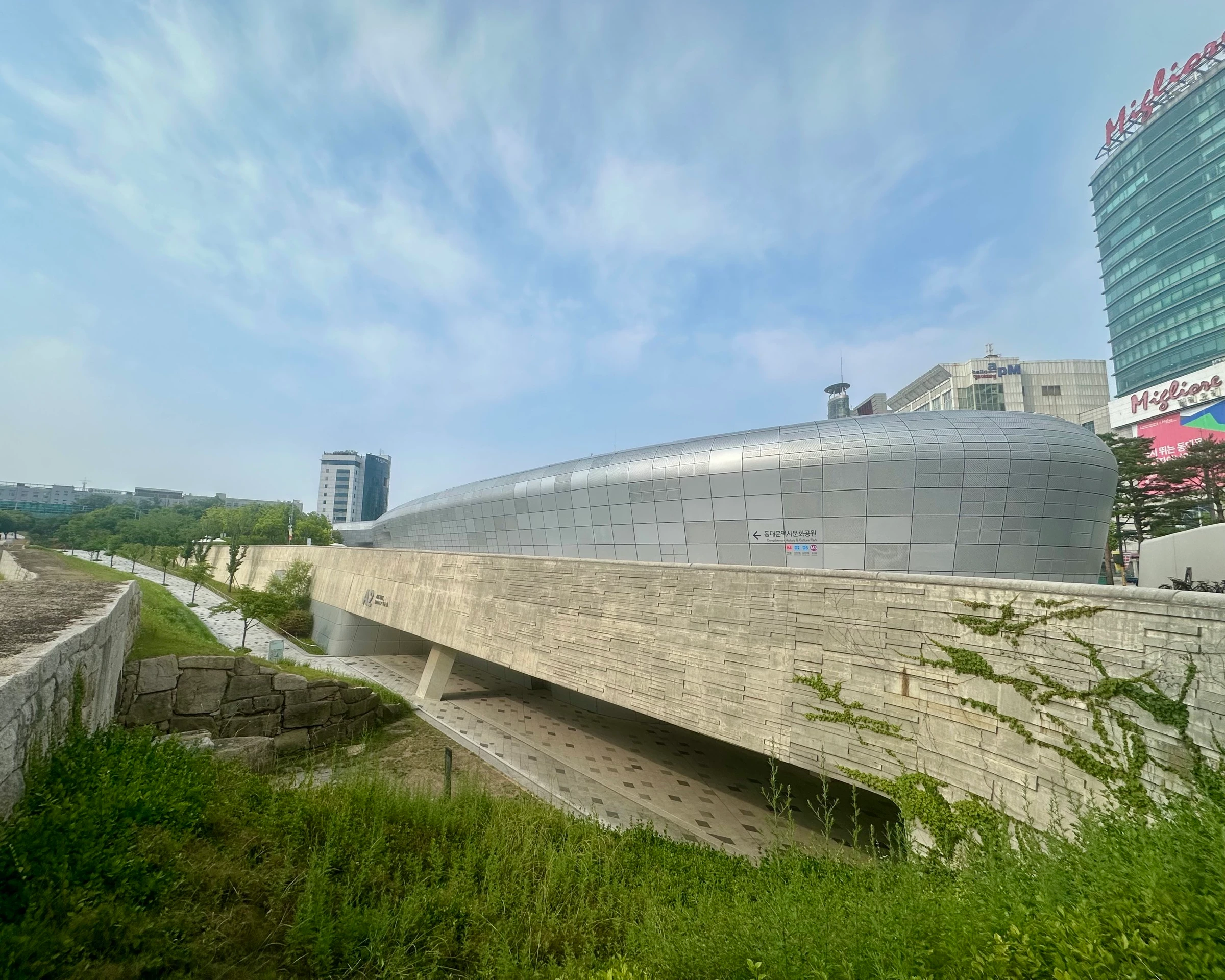 The flowing silver form of Dongdaemun Design Plaza, Zaha Hadid’s neofuturist landmark, rising beside a preserved excavated section of the old Seoul City Wall.