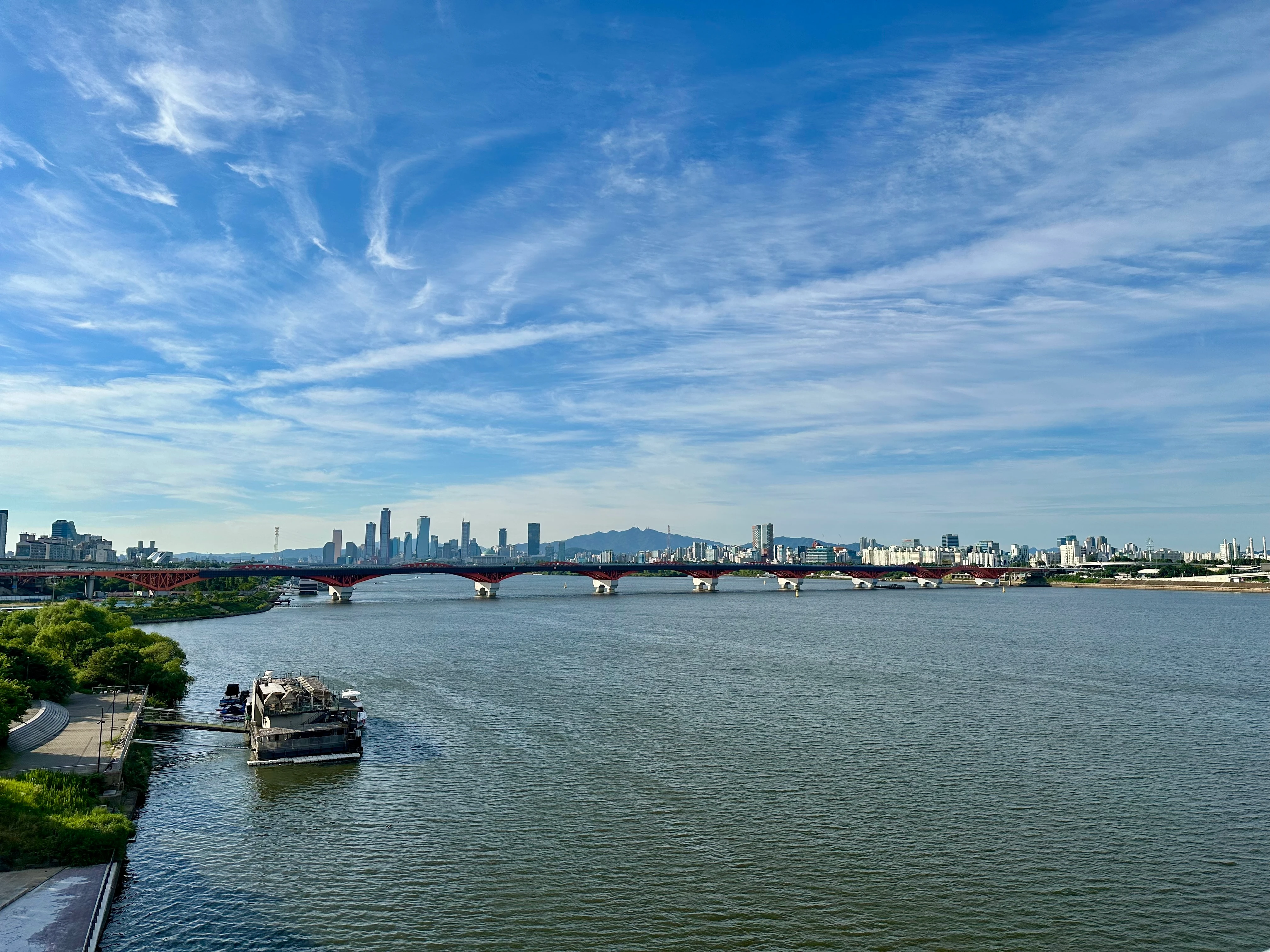 The Yeouido skyline across the Han River from Seongsan Bridge under a dramatic sky.